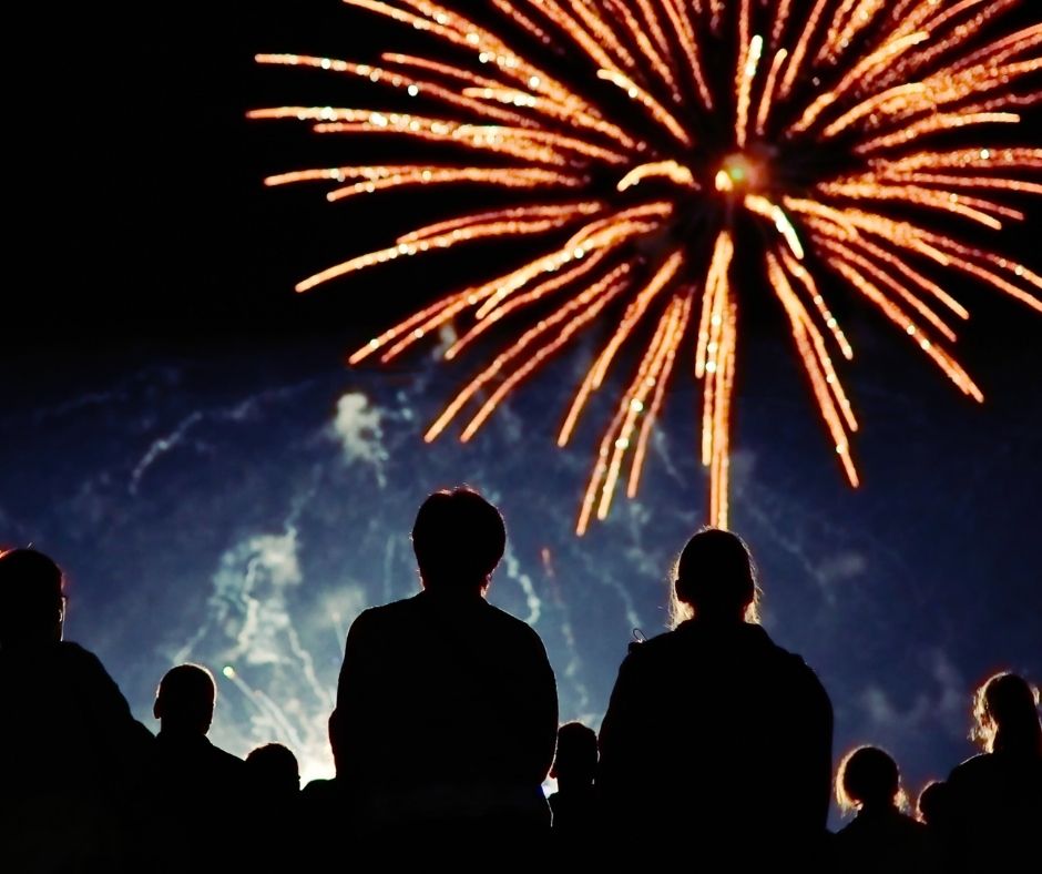 A crowd watches dazzling fireworks light up the night sky, celebrating Mooloolaba NYE with a spectacular beachfront display.