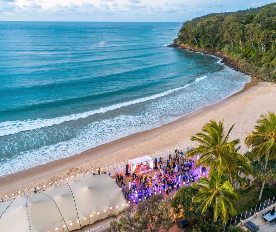A vibrant beachfront festival on the Sunshine Coast, featuring live music, colorful lighting, and scenic ocean views.