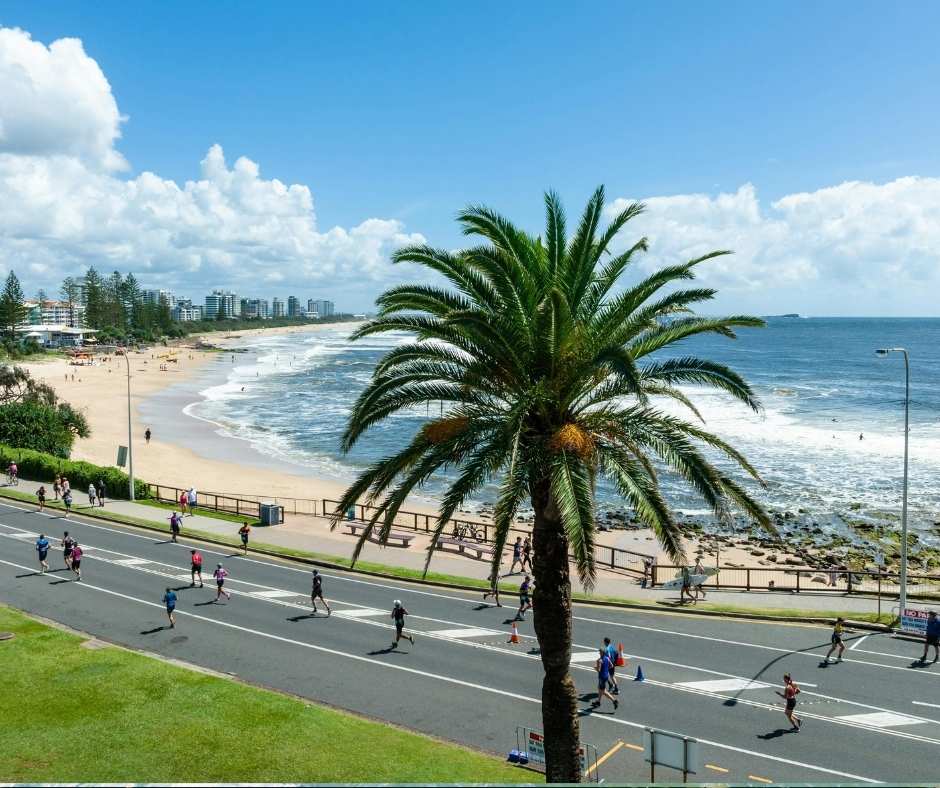 Runners race along the scenic Mooloolaba beachfront during a Sunshine Coast sports event, with stunning ocean views and a vibrant coastal atmosphere.